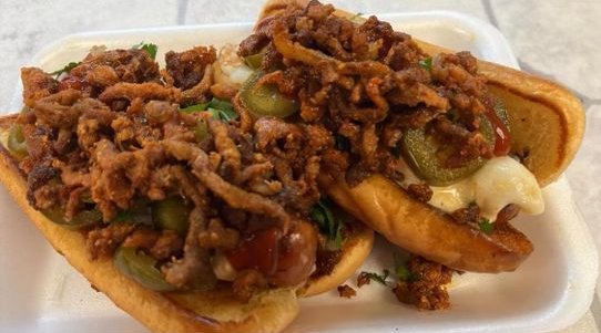 Two bacon-wrapped Mexican hot dogs loaded with toppings and jalapeños