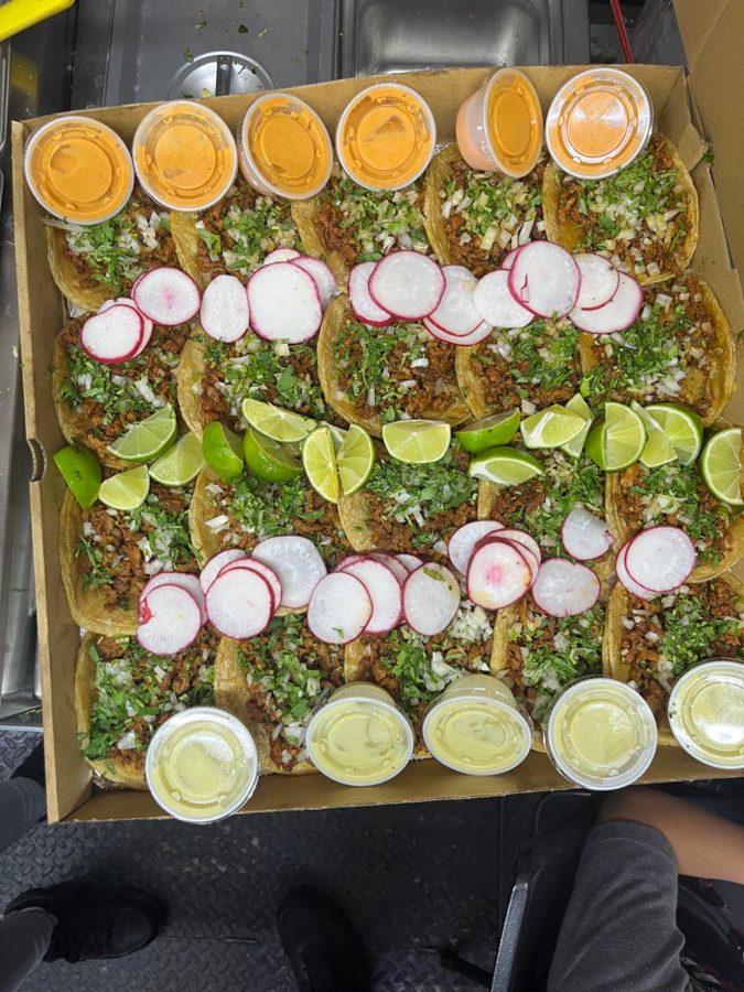 Party tray filled with street tacos, salsas, limes and radishes